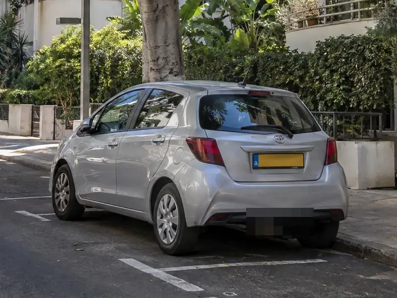 רכב חונה ברחוב. בחצי השמאלי לוחית הרישוי שלו מכוסה בפיקסלים